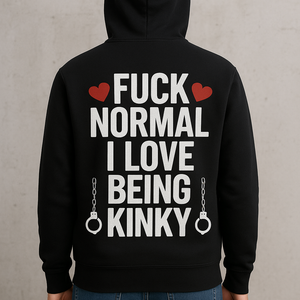 Persoon met rug naar de camera draagt een zwarte hoodie met gedurfde witte en rode tekst: 'FUCK NORMAL I LOVE BEING KINKY', afgewerkt met hartjes en handboeien, tegen een ruwe betonnen achtergrond.